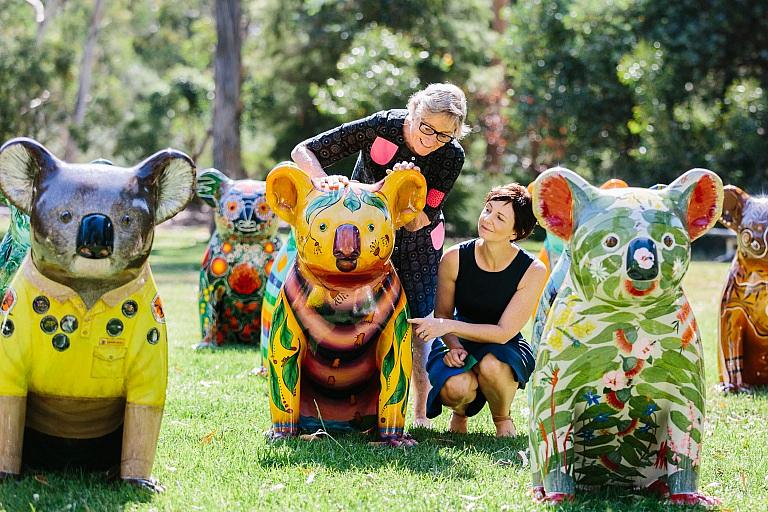 Two women look at koala sculptures