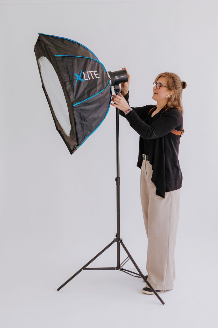 Full body portrait of Alexandra Orme adjusting her studio light
